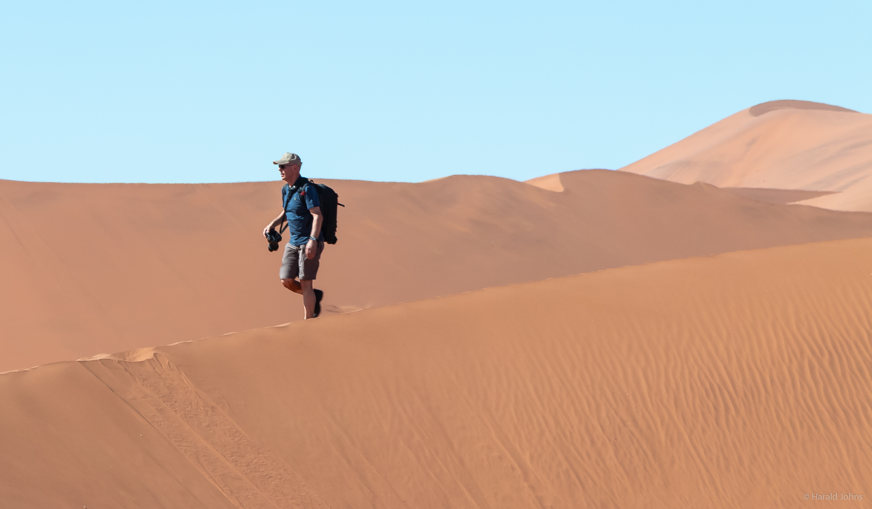 Mit Fotoausrüstung im feinen Sand.